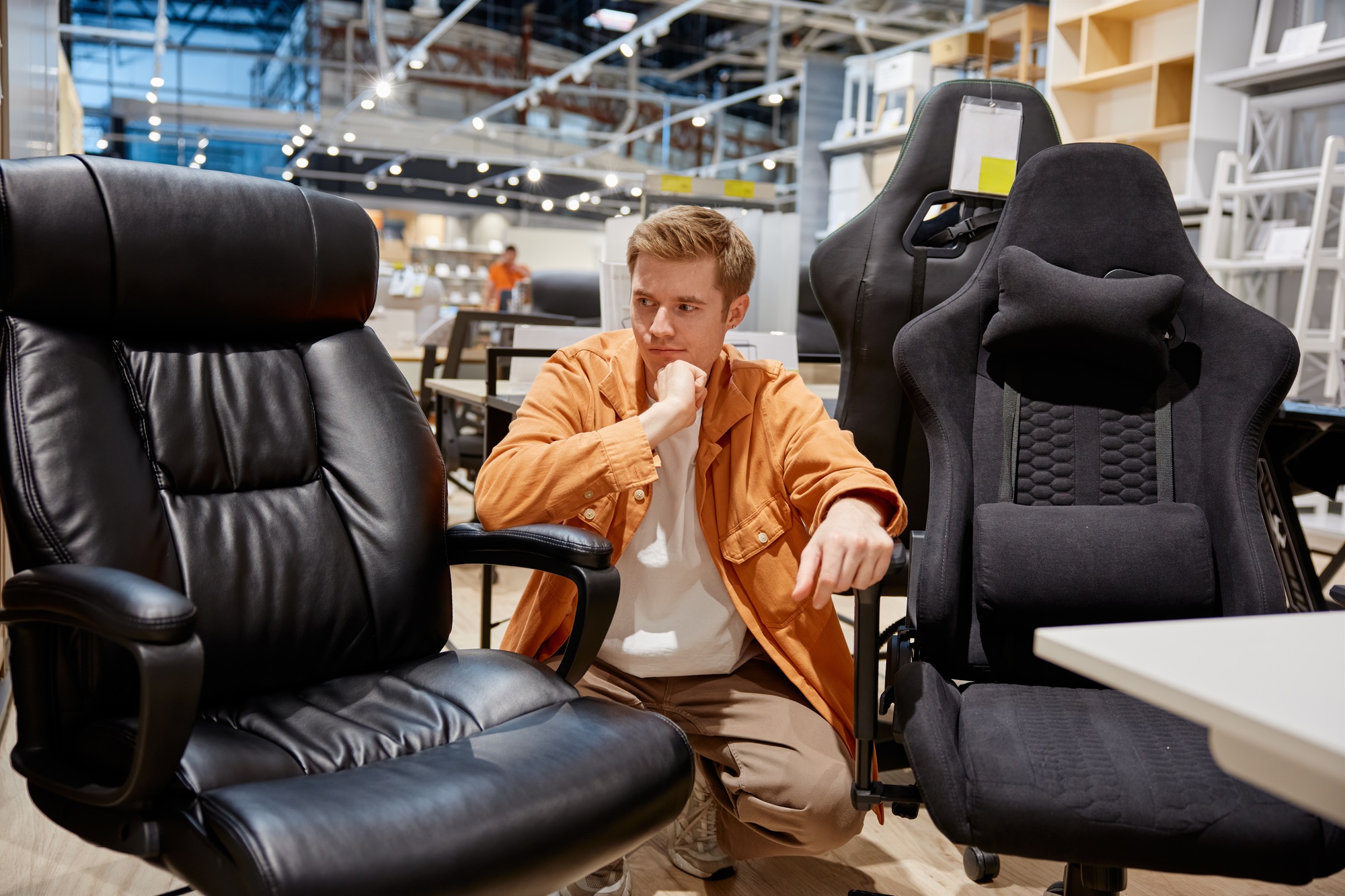 Young handsome man making decision what home office armchair to buy